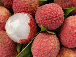 Freshly harvested lychee fruits on a wooden surface with one peeled open.