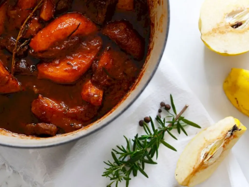 A pot of stewed quince cooked with herbs and spices, perfect for savory winter meals.